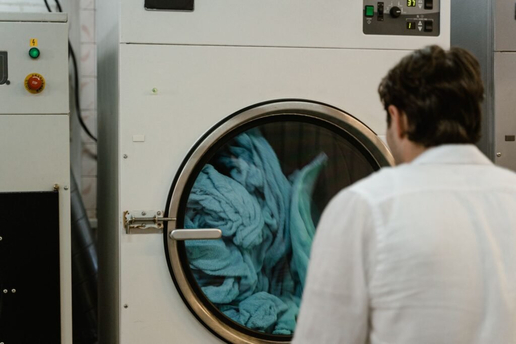 Person watching a washing machine mid-cycle in a laundromat