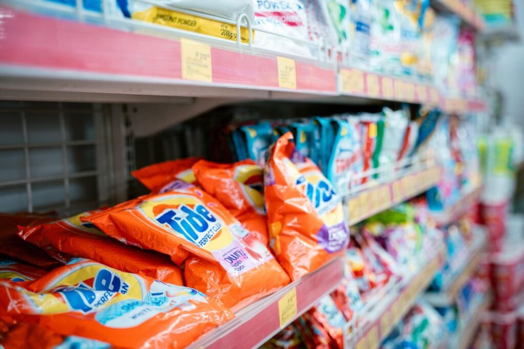 Laundry detergent packs on a supermarket shelf, where the choice between HE and regular detergent is made