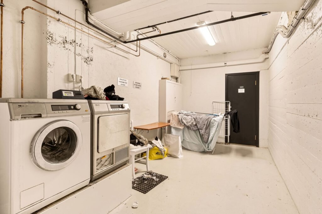 A laundry room with the washing machine and its exposed drain piping, where you drain a washing machine manually