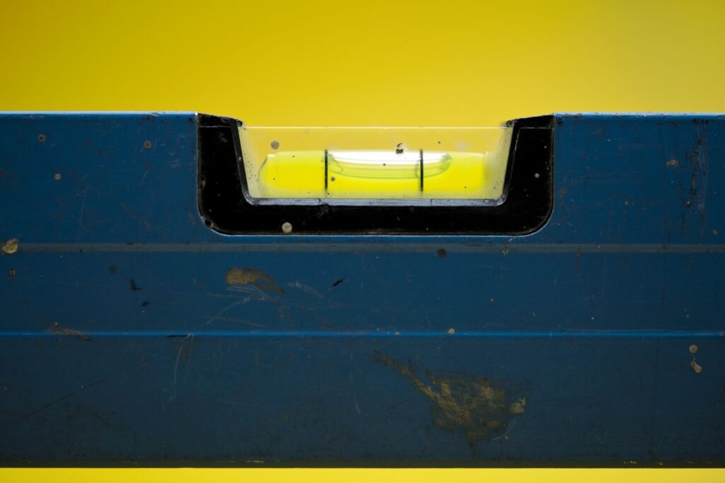 A spirit level with the bubble centred in its vial, the tool and the target for levelling a washing machine