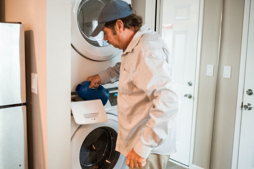 Man pouring liquid detergent into a stacked washer and dryer, relevant to a Samsung washer Auto Dispense not working issue