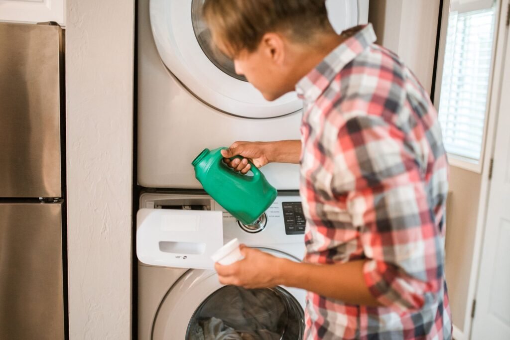 Man pouring liquid detergent into a front-loading washing machine, relevant to a Samsung washer Sud or 5d oversudsing error