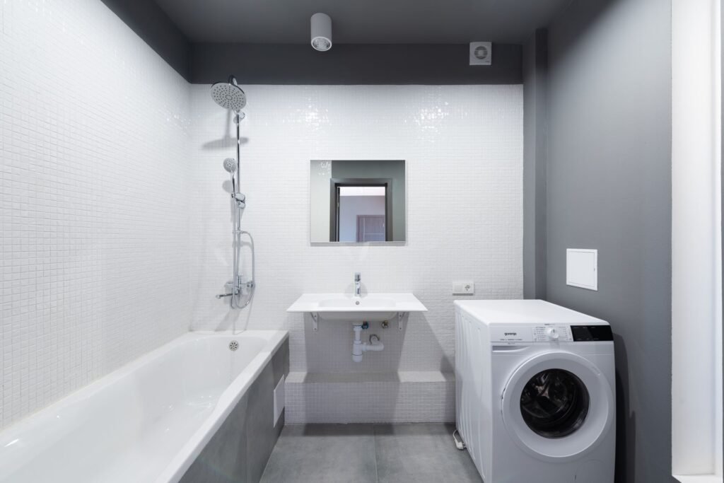 A washing machine plumbed in beside a bath and basin, where the hot and cold supply lines are easily crossed