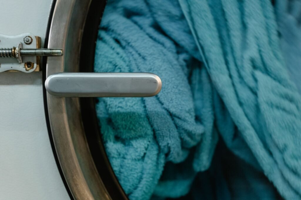 Blue cotton towels behind the closed door of a front-load washer, the kind of load a sanitize cycle suits