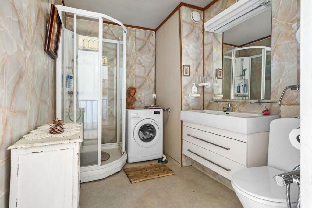 A front-load washing machine in a home bathroom, showing the small control panel where an unlisted code appears
