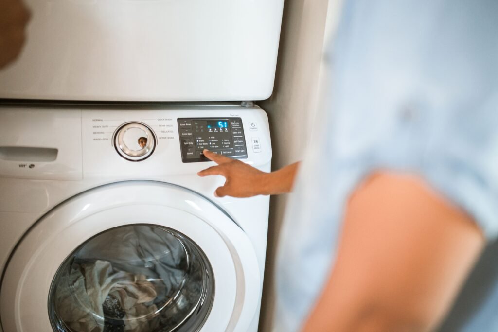 Hand pressing a button on a lit washing machine control panel that will not begin a cycle