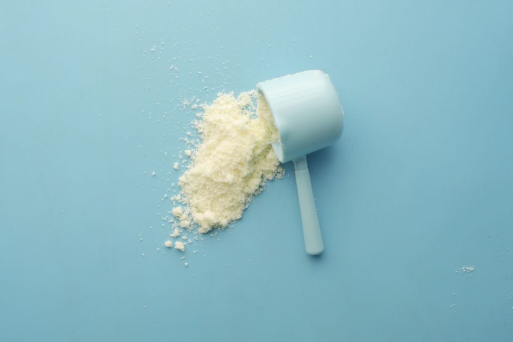 White powder spilling from a measuring scoop, the half cup of baking soda added to a laundry load