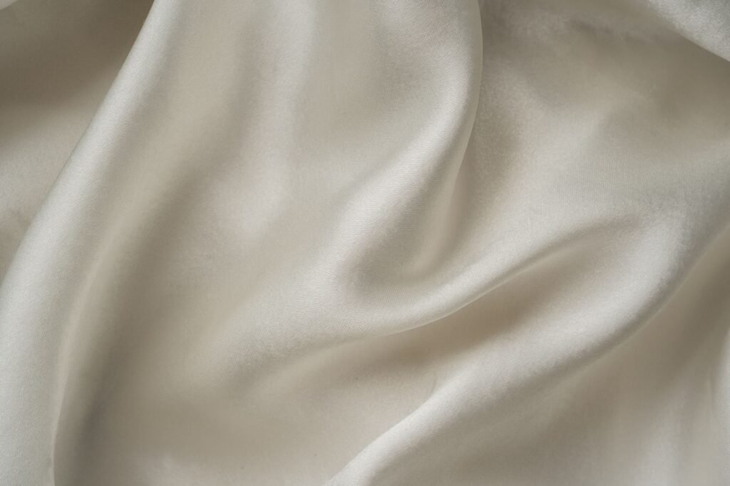 Close-up of smooth white silk fabric in soft folds, the protein fibre that decides every rule for washing silk