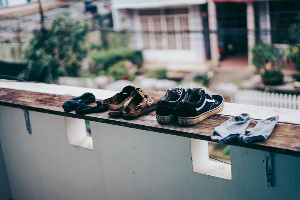 Sneakers, sandals and socks air drying outdoors on a ledge, the alternative to putting shoes in a tumble dryer