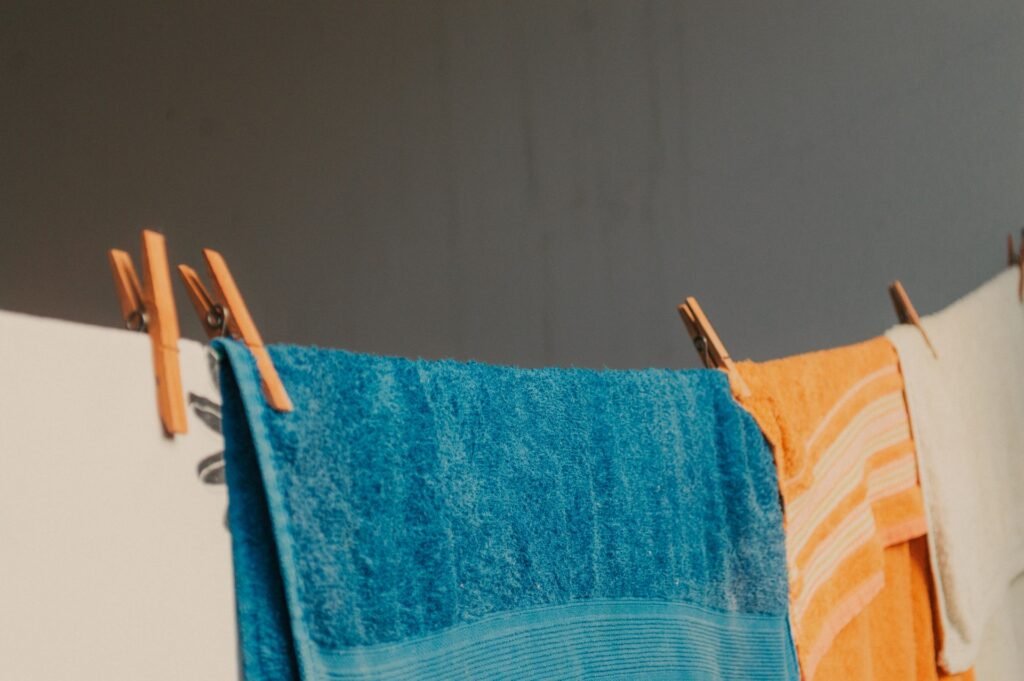 Brightly coloured towels hanging on an indoor line, the kind of load where the choice between dryer balls and dryer sheets matters