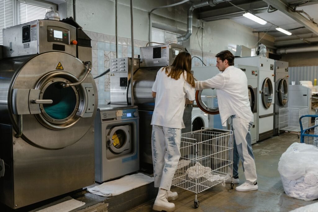 An industrial laundry room with tumble dryers and exhaust ducting running overhead