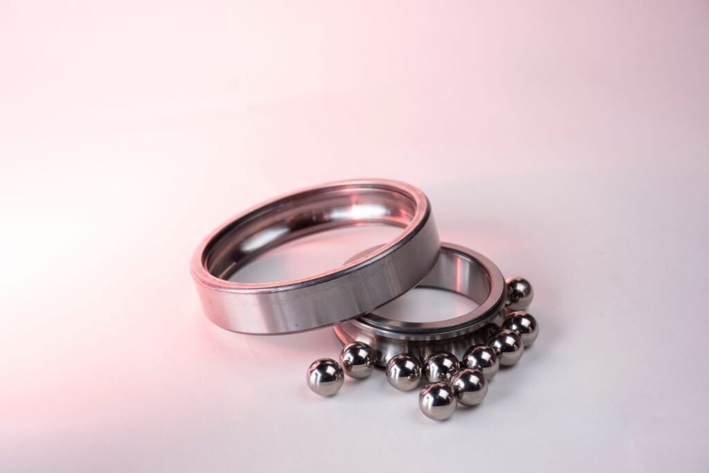A stainless steel ball bearing taken apart, its race rings and loose balls laid out