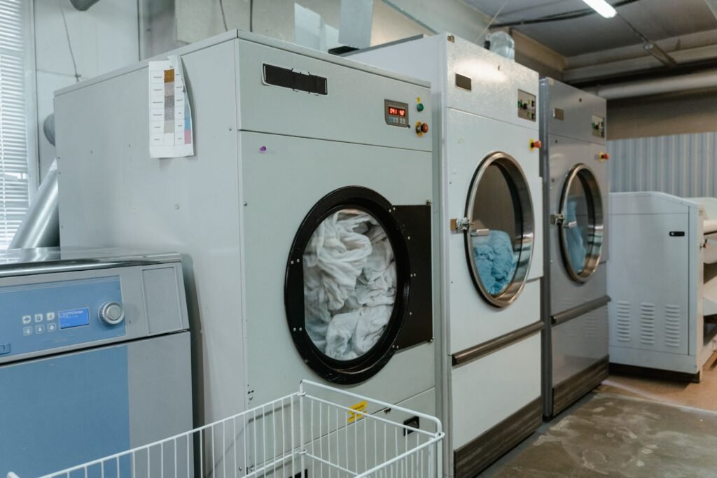 Industrial dryers in a laundry room with exhaust ducting running overhead, the airflow path that decides drying time