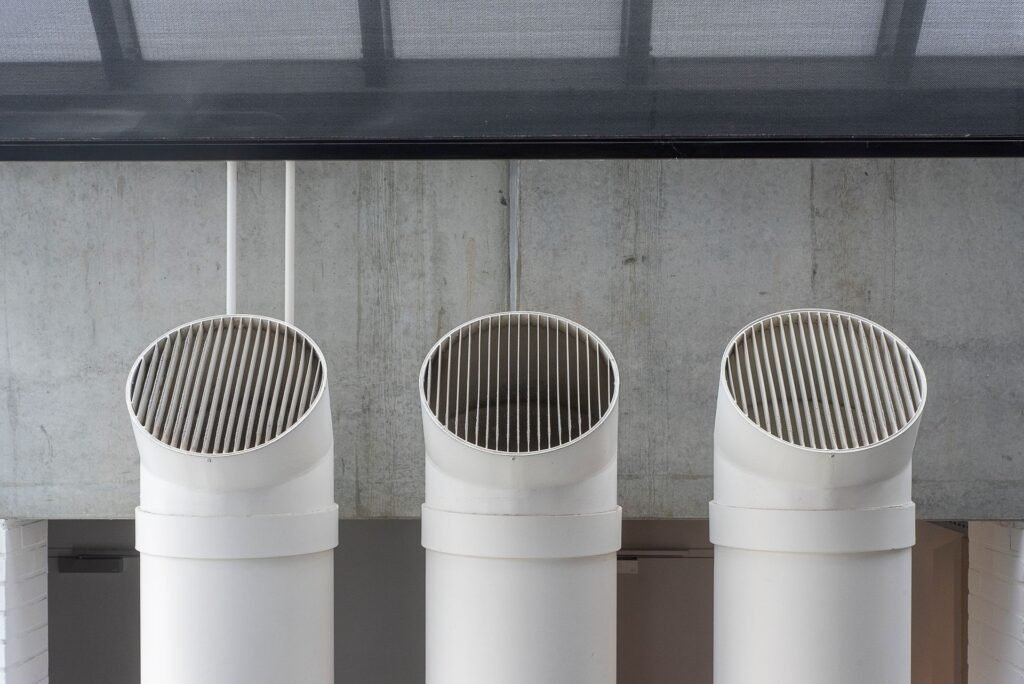 Three white exhaust ducts running up a concrete exterior wall, the kind of vent run that decides what a cleaning costs