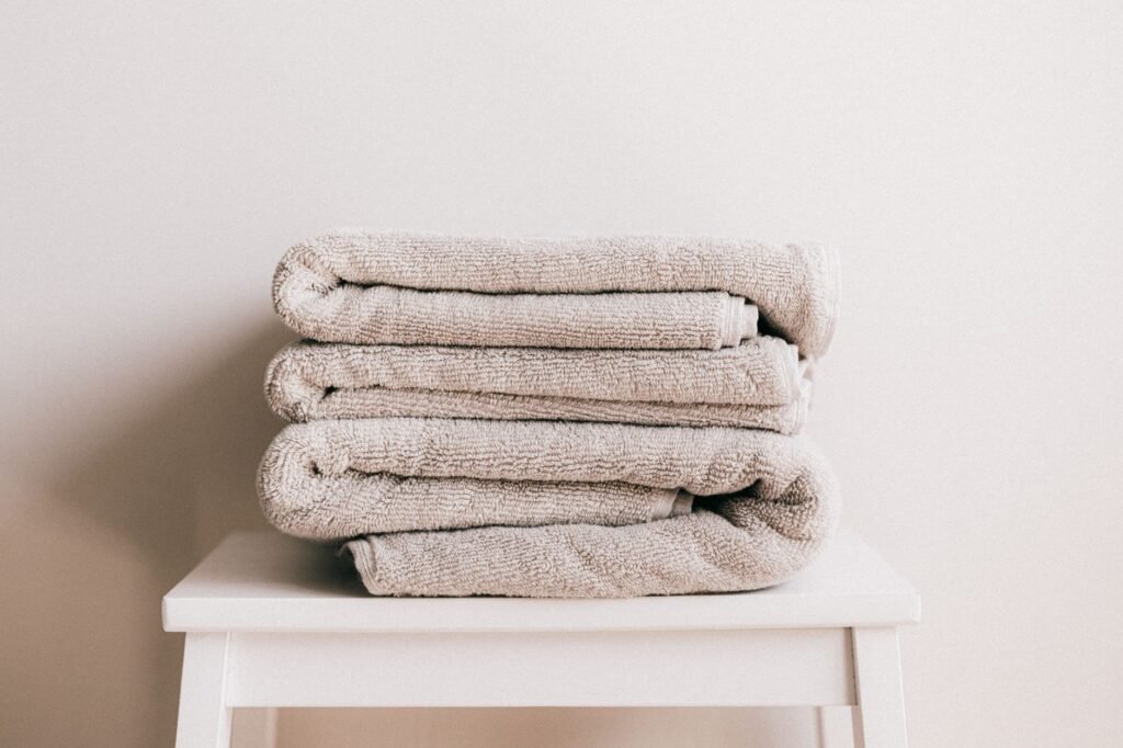 Stack of soft folded beige towels on a stool, the softness both fabric softener and dryer sheets promise