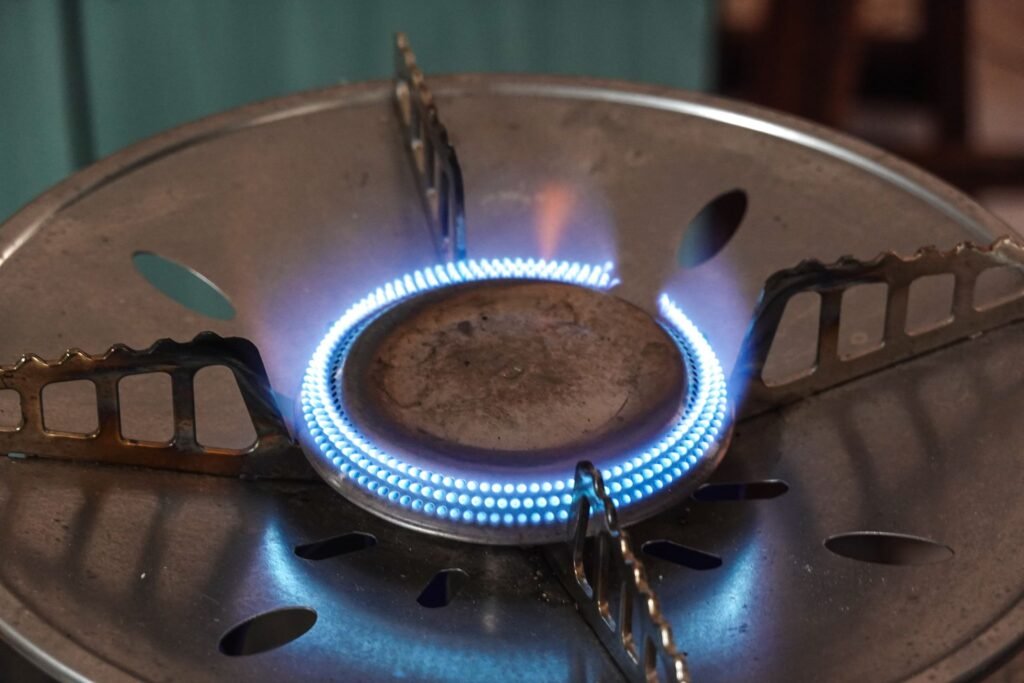 A gas burner alight with a ring of blue flame, the flame a gas dryer's igniter has to start