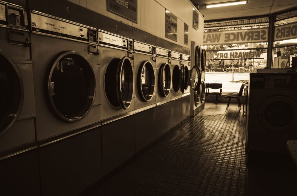 A sepia-toned launderette lined with well-used washing machines, the kind that have run for years