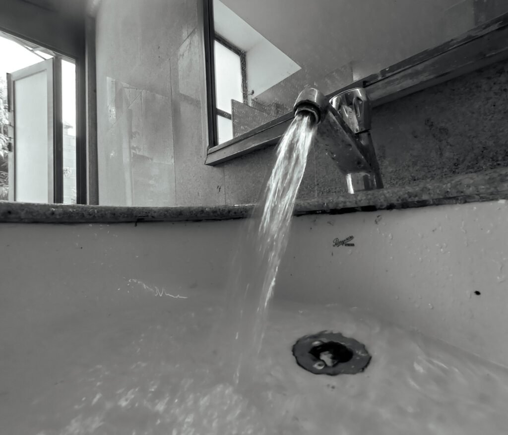 Water running hard from a tap into a basin, shot in black and white