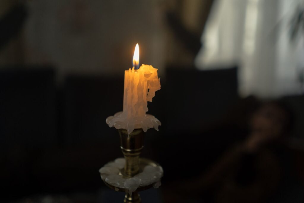 Close-up of a burning candle with melted wax running down the side, the moment before it drips onto fabric