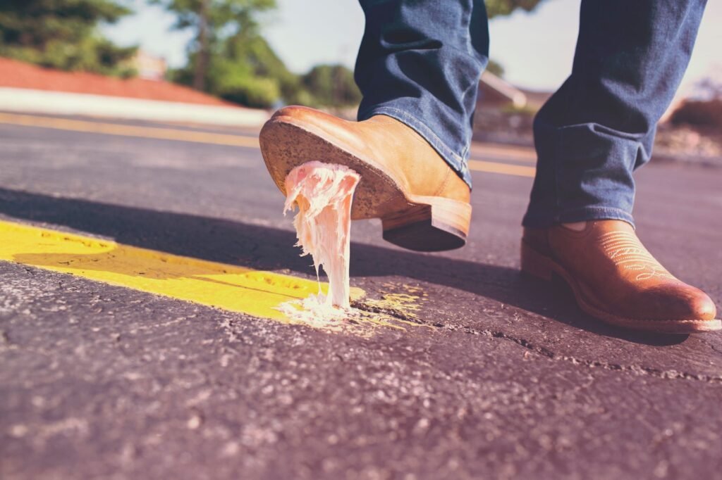 Close-up of a shoe stepping on chewing gum stuck to a pavement, the everyday mishap behind this stain