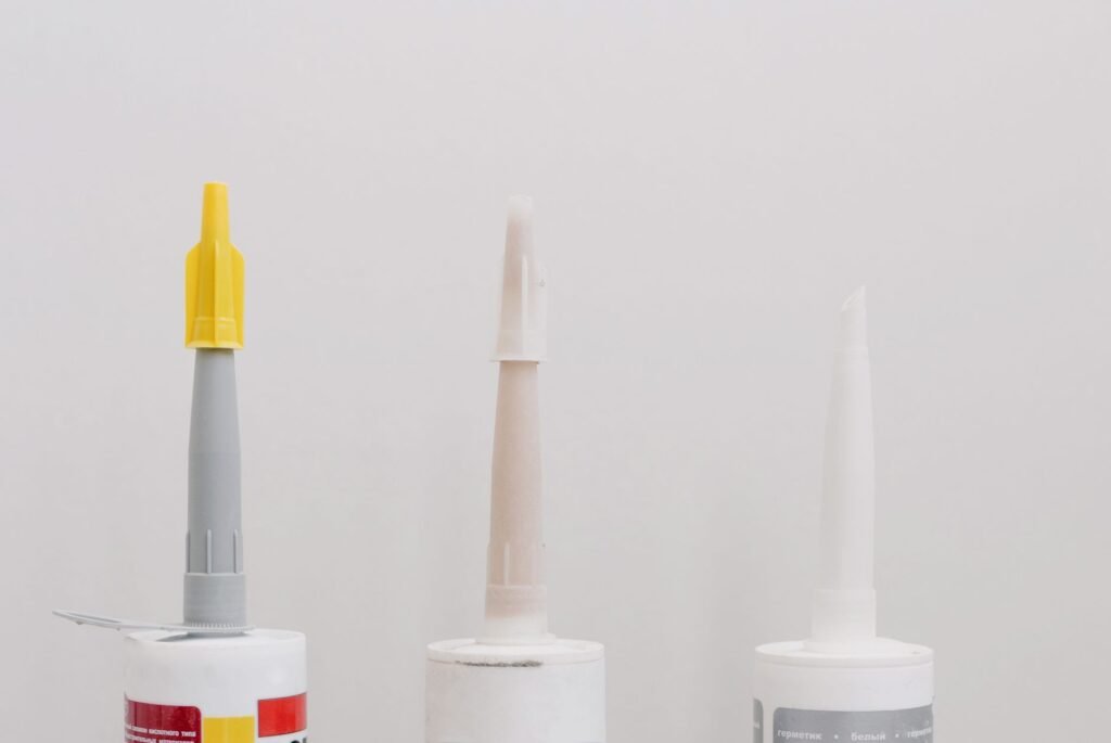 Row of assorted adhesive and glue tubes on a white workbench, the different adhesives this stain guide covers