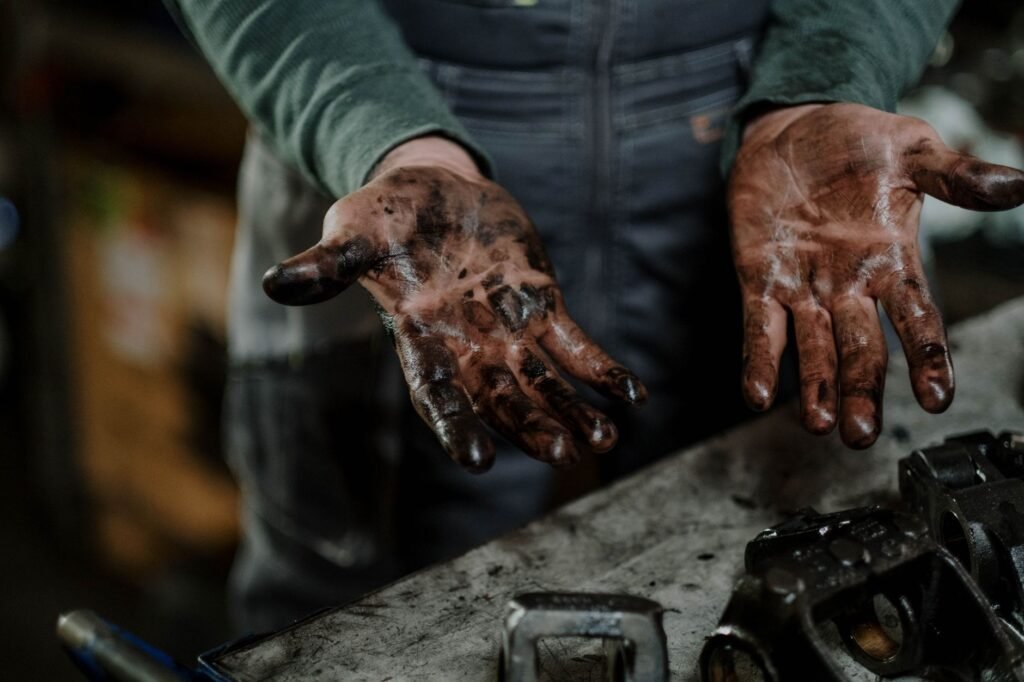 Close-up of a mechanic's oil-stained hands in a garage, the usual source of motor oil stains on workwear