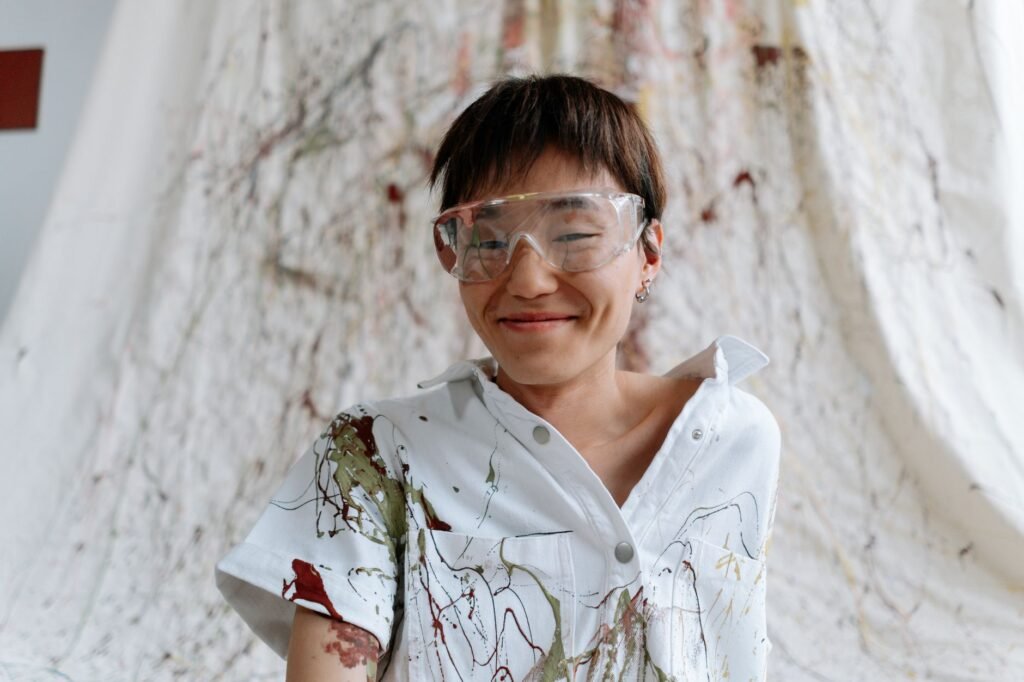 Artist in safety glasses wearing a white shirt covered in paint splatters, the stain this guide removes