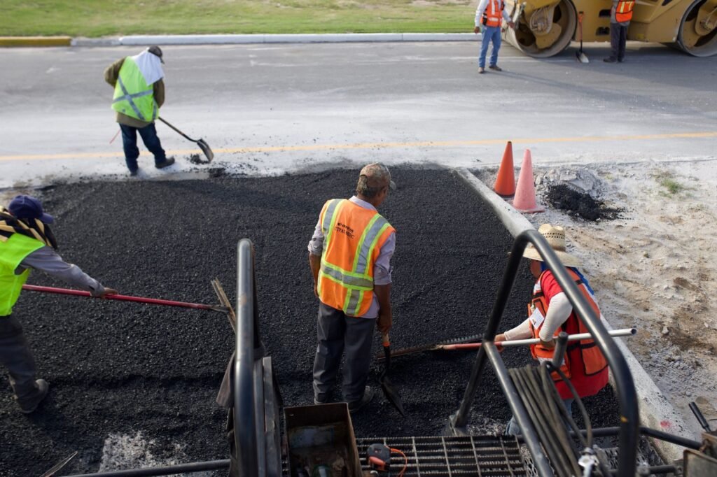 Road crew in work clothes laying fresh black asphalt, the most common source of tar stains on clothing