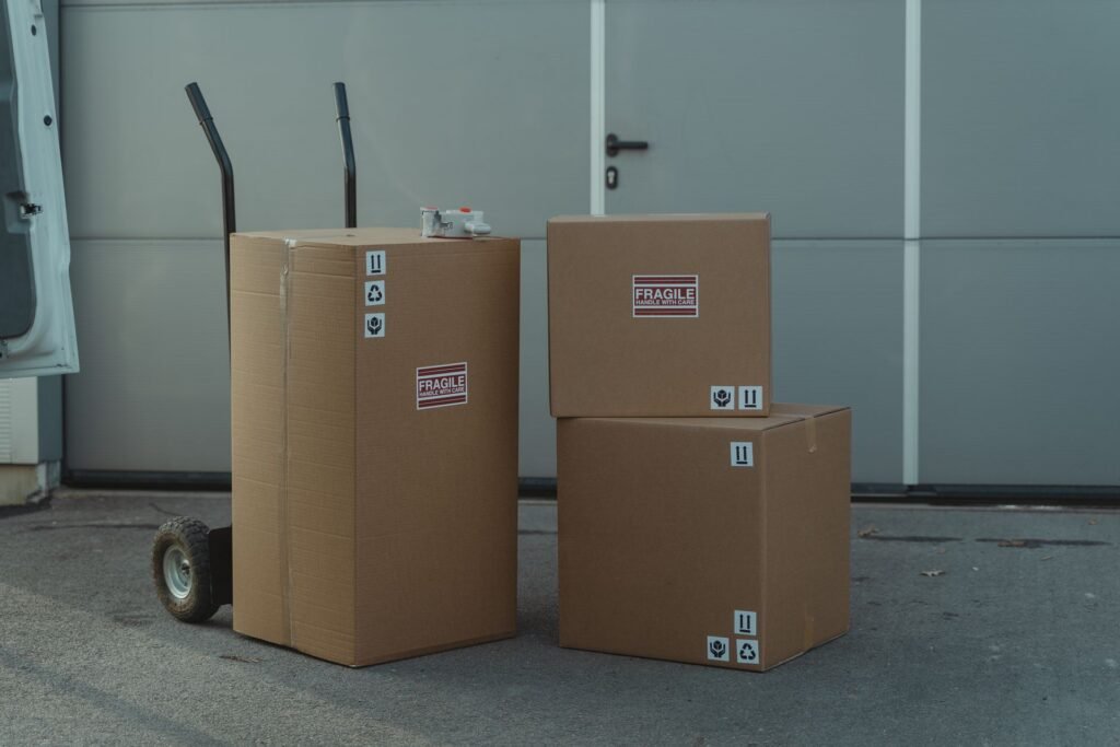 Boxes marked fragile strapped to a hand trolley beside an open van, ready for a move