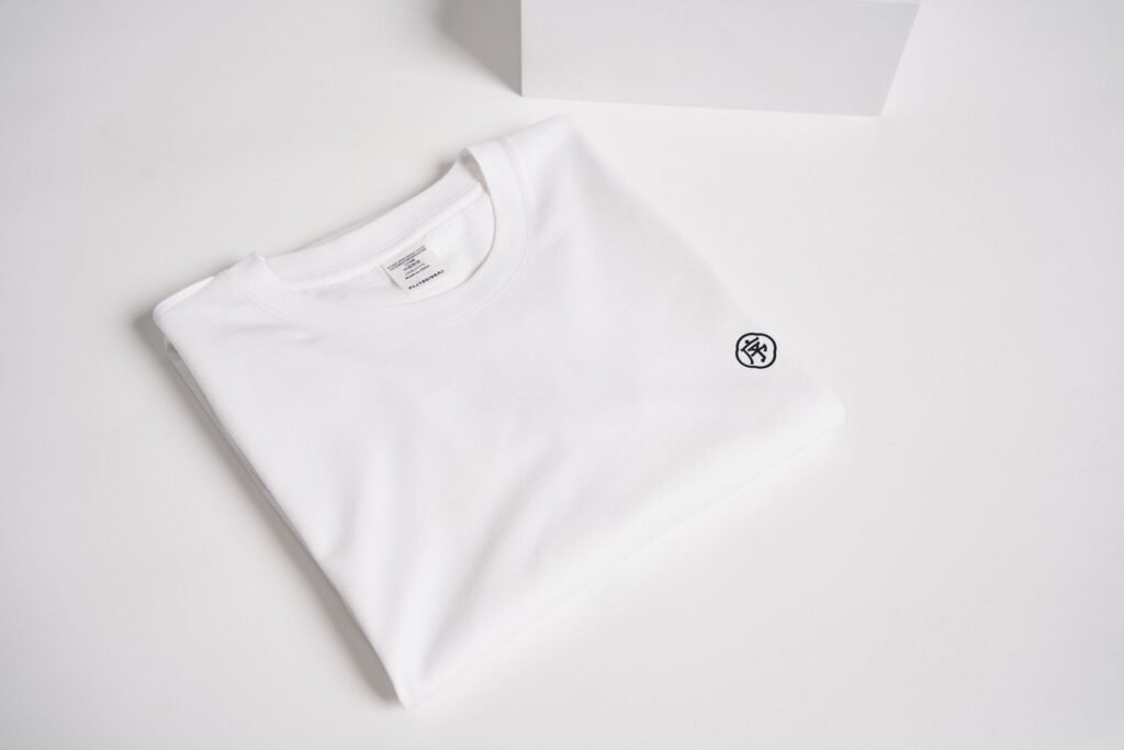 A plain white t-shirt folded on a white surface, the garment underarm marks show up on first