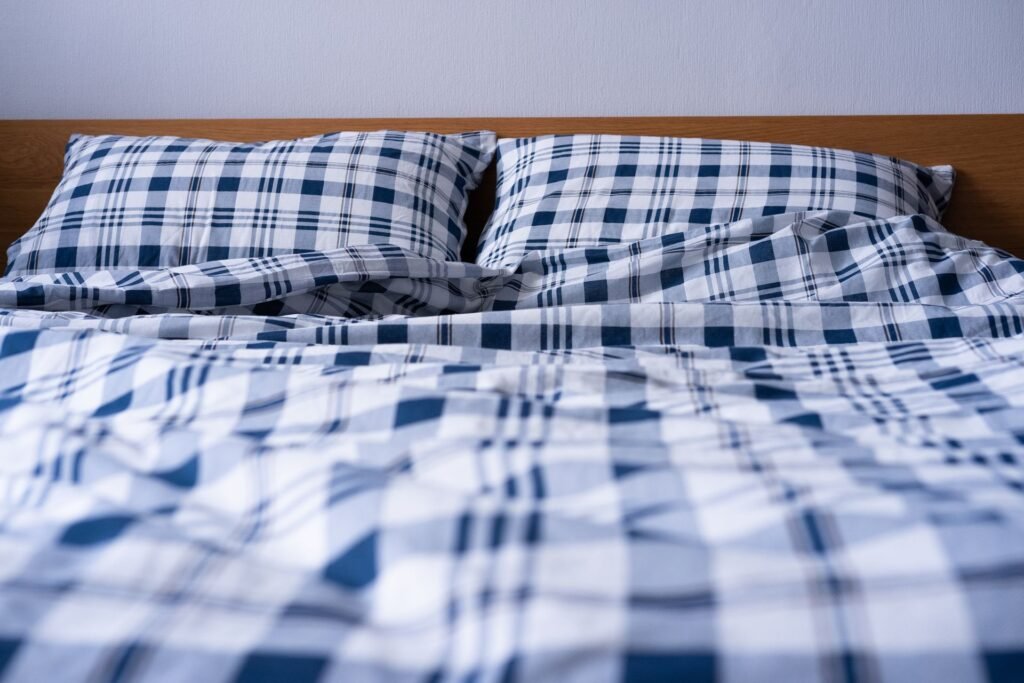 A double bed made up with blue plaid bedding, the bulk that has to fit in a drum