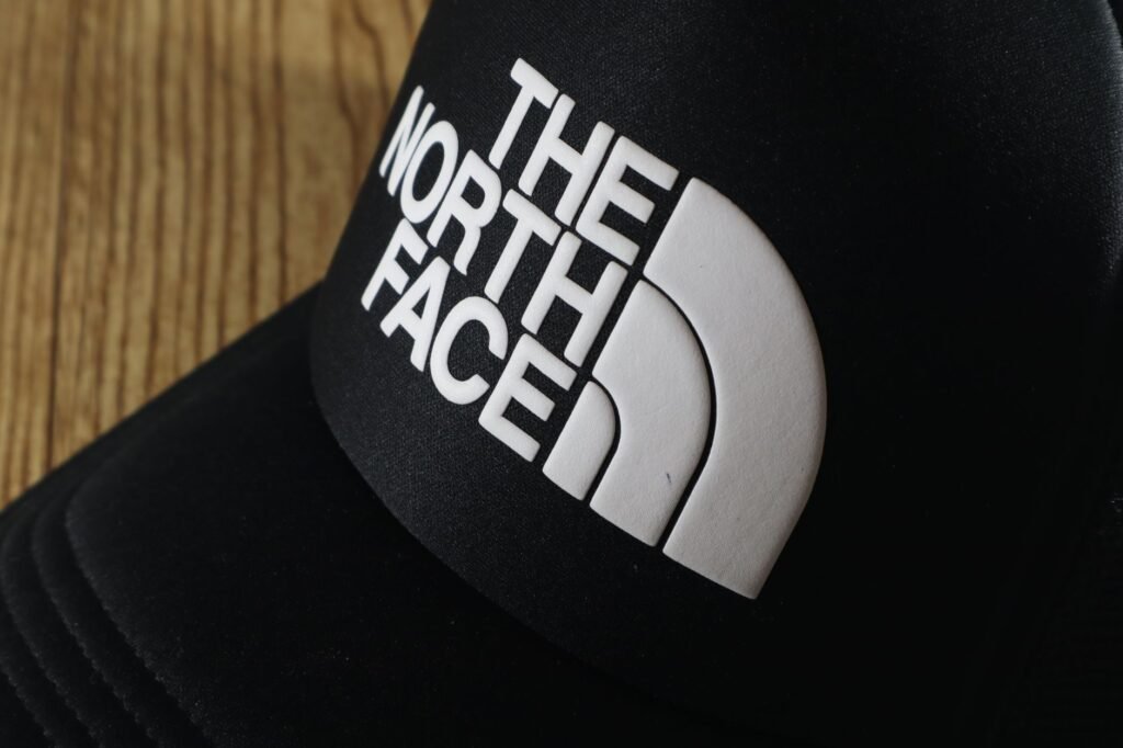 Close-up of a black baseball cap on a wooden surface showing the stitched brim that decides how a hat can be washed