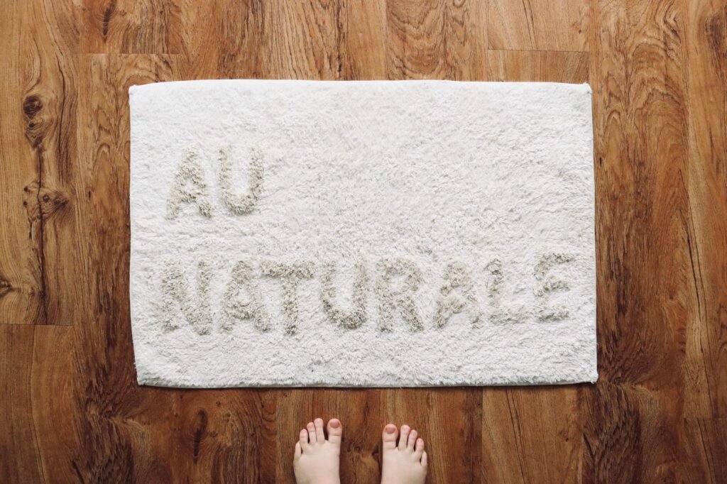 White doormat on a wooden floor seen from above, the size of rug that fits in a domestic washing machine