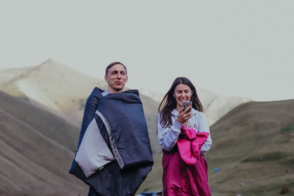 Two campers wrapped in sleeping bags on a mountainside, the loft that washing a sleeping bag badly destroys