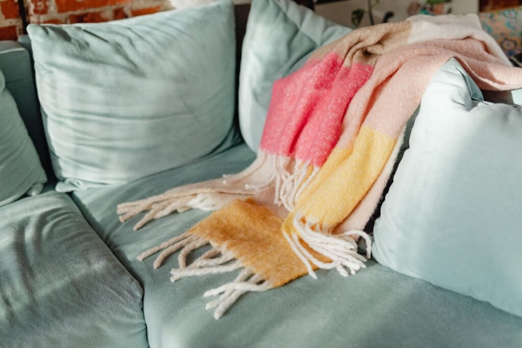 Soft folded blanket thrown over the arm of a sofa, the kind of heated throw that needs a cold gentle wash