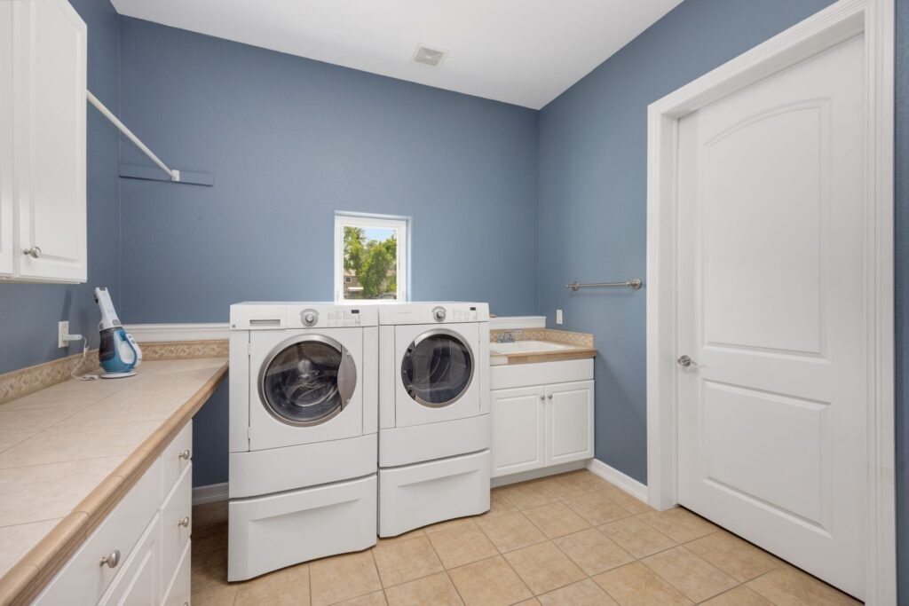 A washer and dryer pair standing side by side in a blue-walled laundry room