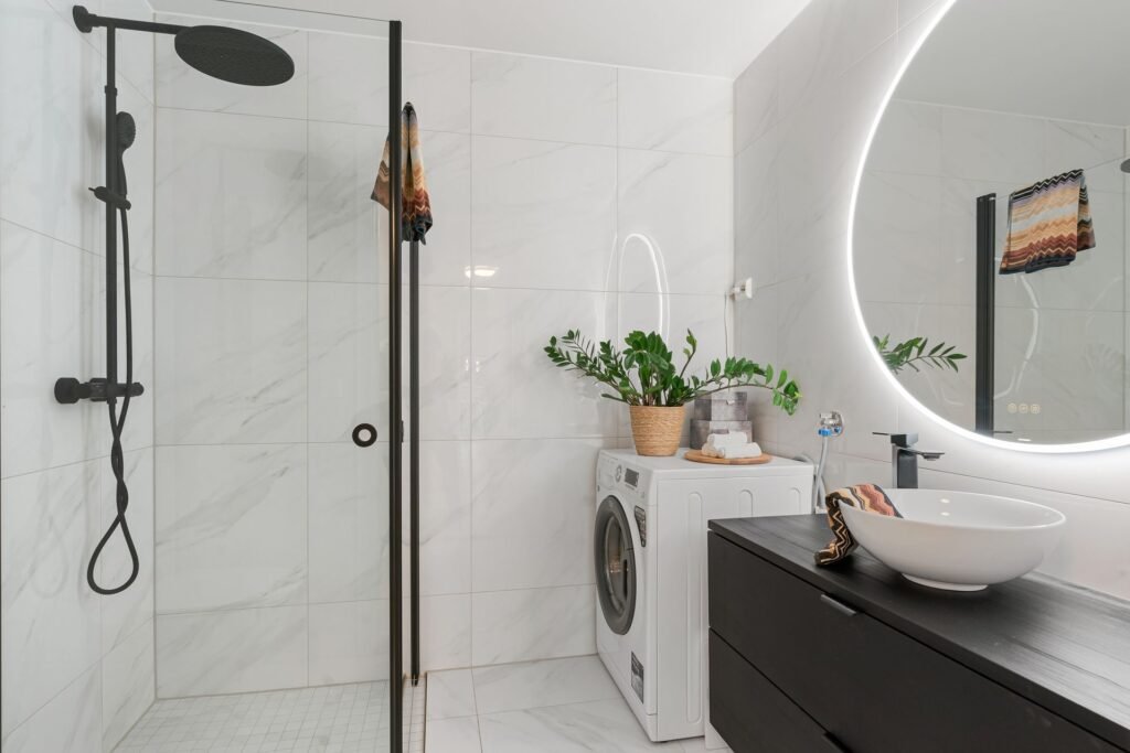 Front-load washing machine built into a modern bathroom, a humid room where a closed drum dries slowly
