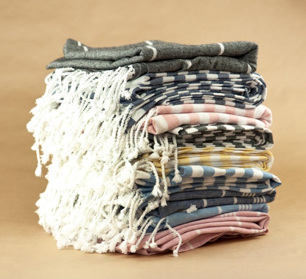 A stack of folded striped towels with fringed ends, the pile that comes out board-stiff after a wash