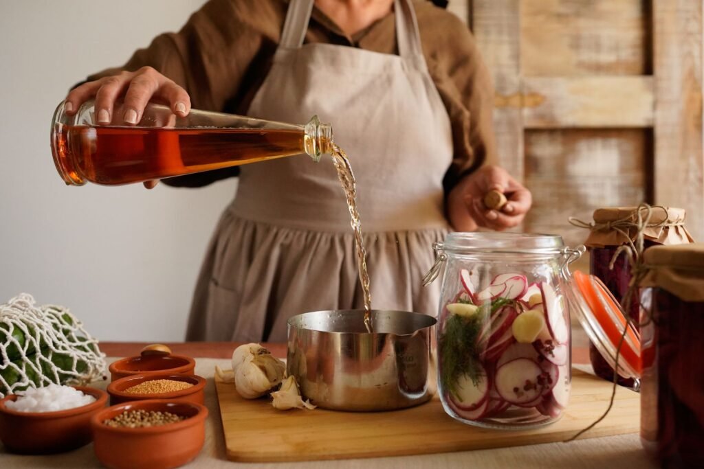 Vinegar being poured from a glass bottle in a kitchen, the same household bottle people reach for when a washer smells