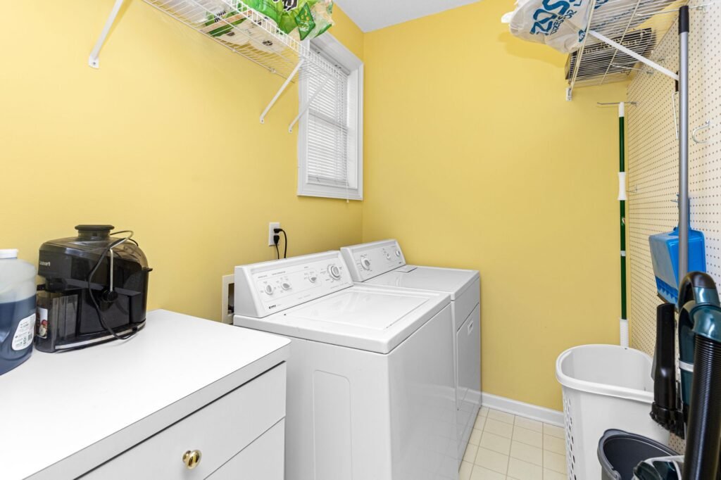 Bright domestic laundry room with a washer and dryer on a tiled floor, the floor a washer drain pan is meant to protect