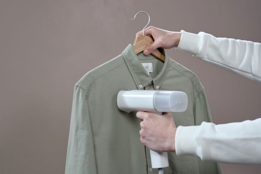 Handheld steamer relaxing the fibres of a cotton shirt, the same softening effect a washer steam cycle produces