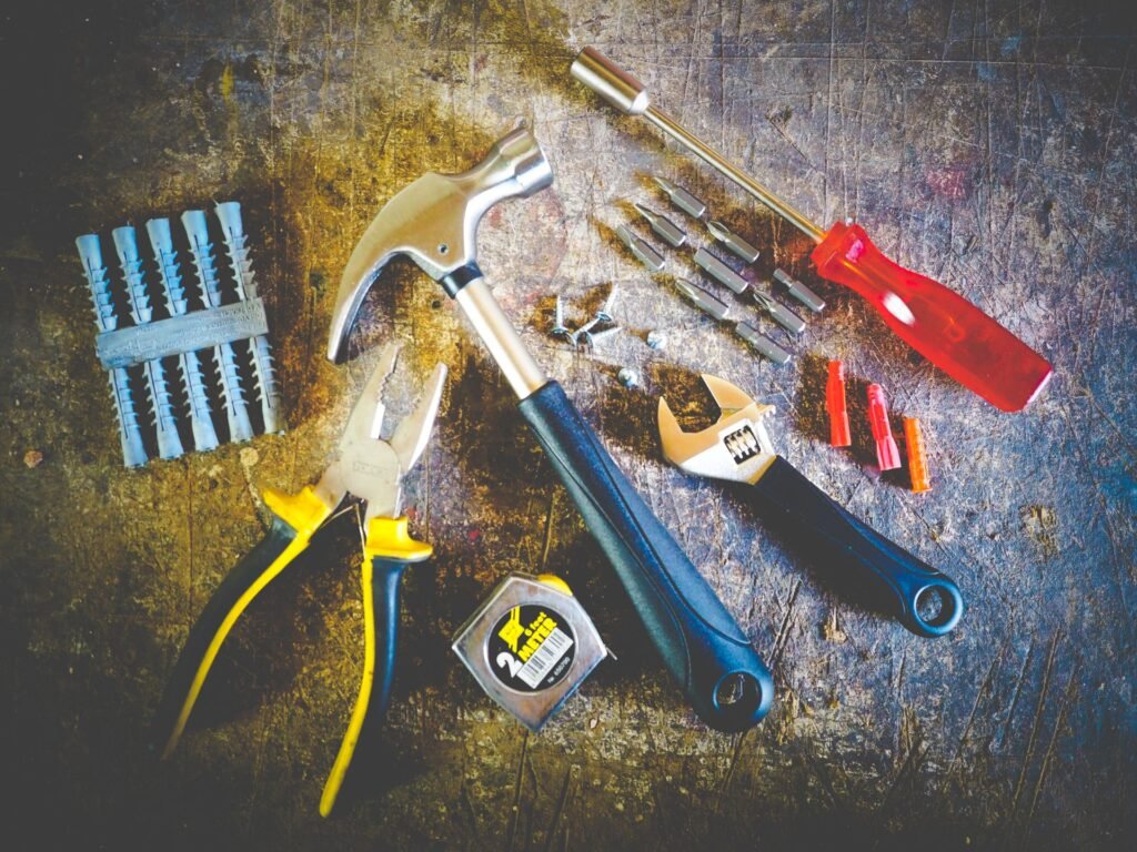 Hand tools laid out on a workbench, including pliers, an adjustable wrench and screwdriver bits