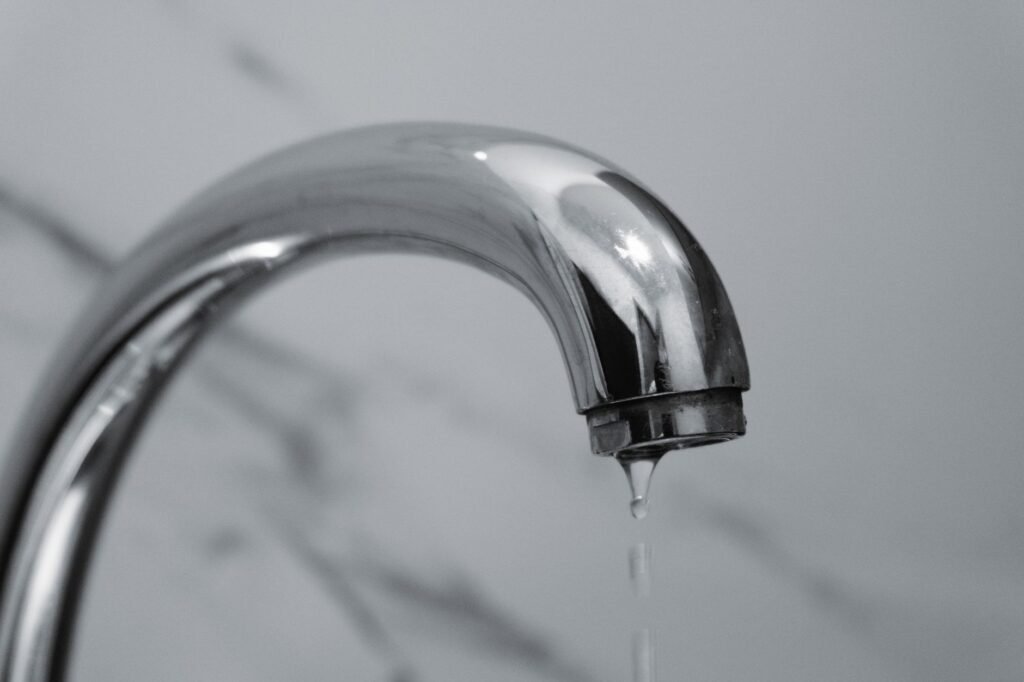Water dripping slowly from a chrome tap, the restricted supply that leaves a washer filling too slowly