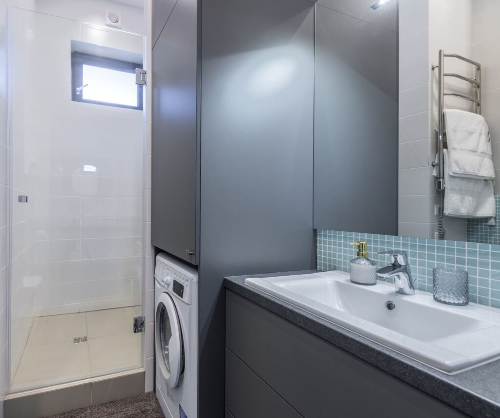 Front-load washer built into a tiled bathroom, where floor and cabinet rigidity decide how much a spin is felt