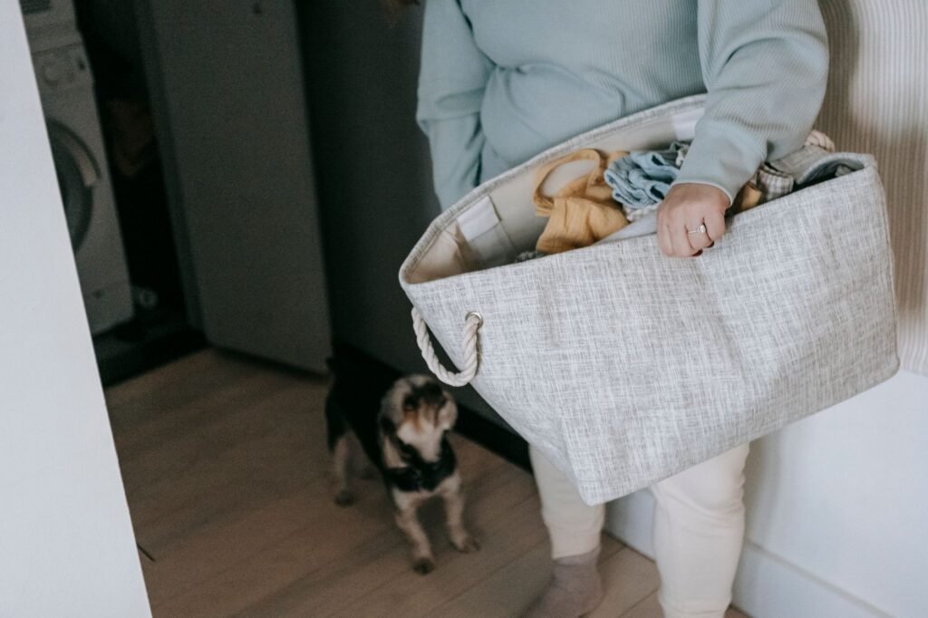 Person carrying a full fabric laundry basket past a washing machine, the load size that decides whether it will spin