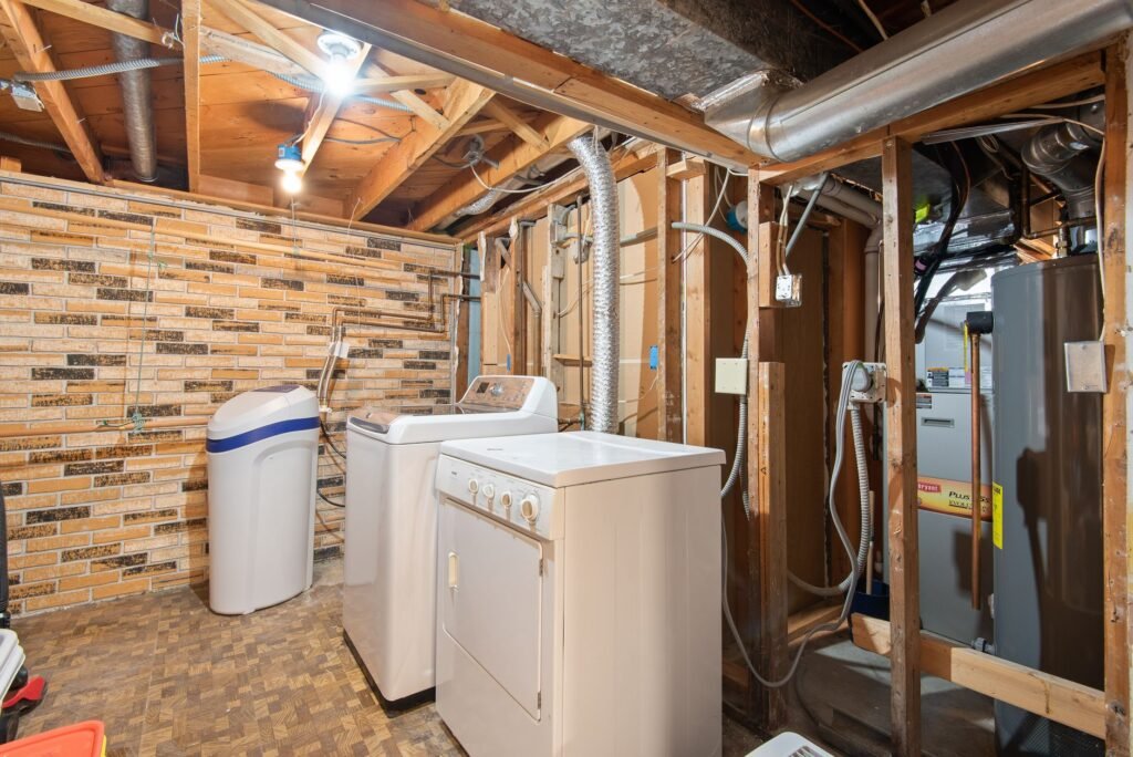 Washer and dryer in a basement laundry room with exposed brickwork, where a washing machine standpipe is usually visible