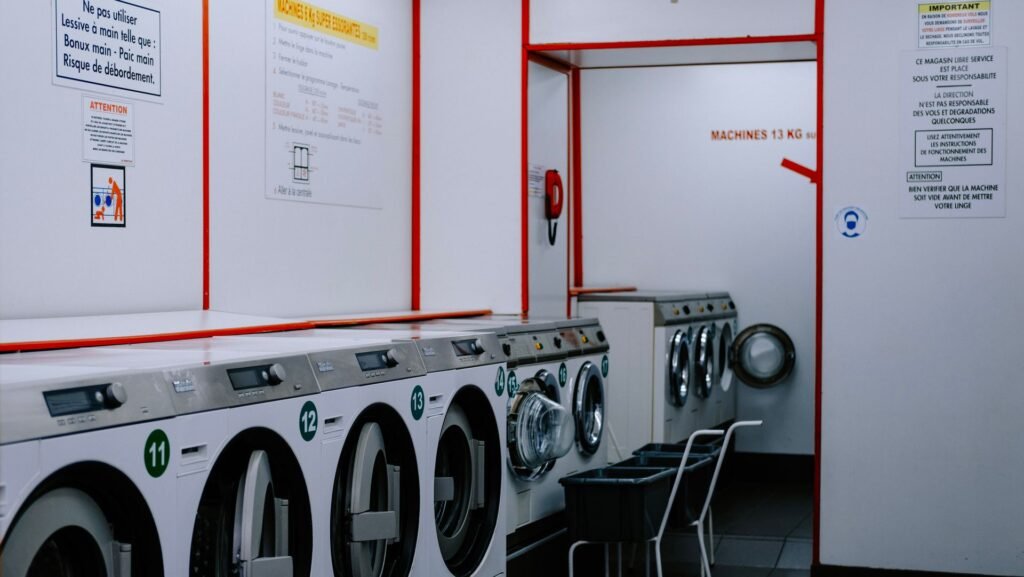 A launderette lined with numbered machines and instruction notices on the wall