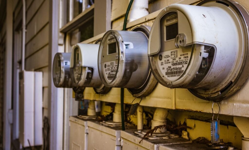 Four GE SmartMeter electricity meters bolted to a yellow exterior wall, one of them stamped 240V, the supply a standard electric dryer runs on