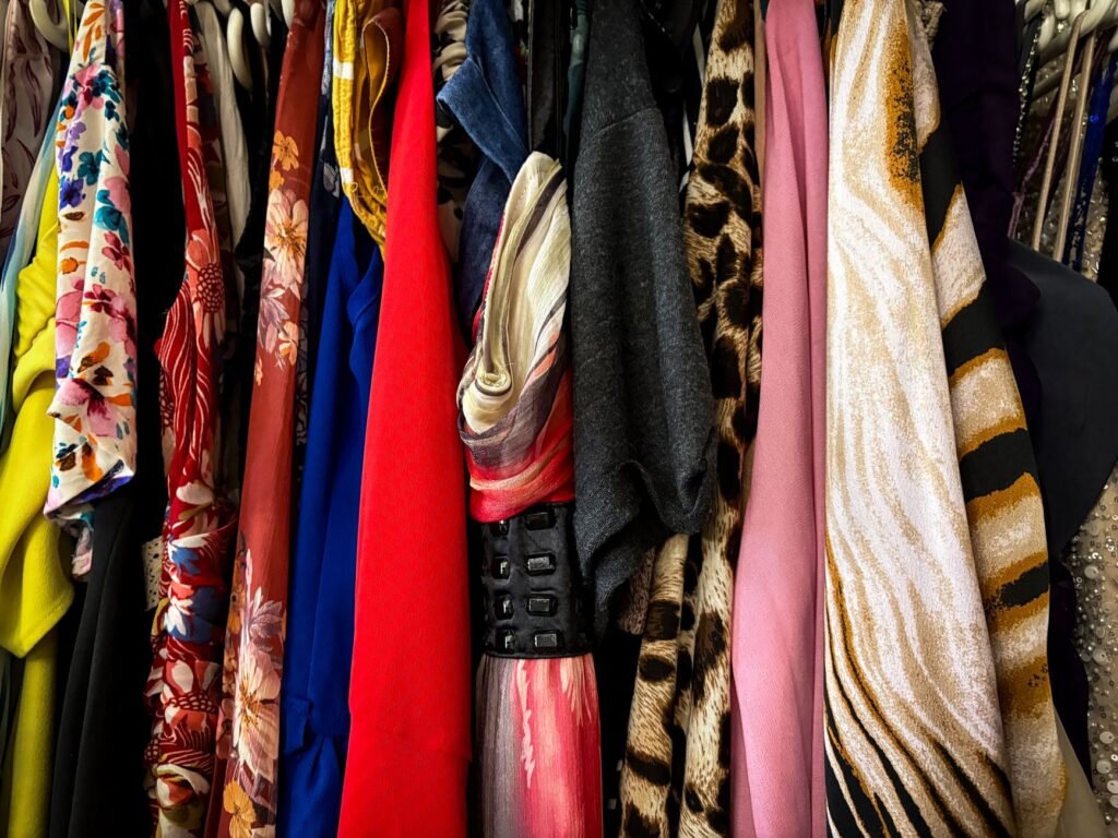 Densely packed rack of vintage garments in saturated prints, including florals, animal print, metallic stripes and a sequinned sleeve