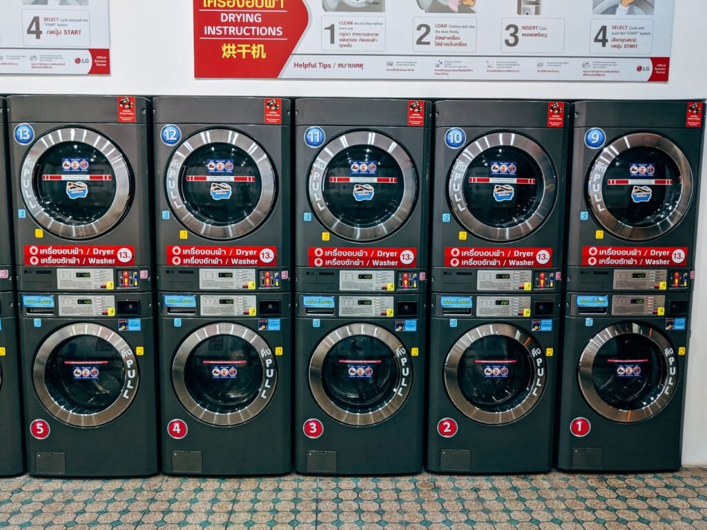 A bank of stacked LG washer and dryer units in a laundrette, each dryer control panel showing a lit green countdown above its coin slot